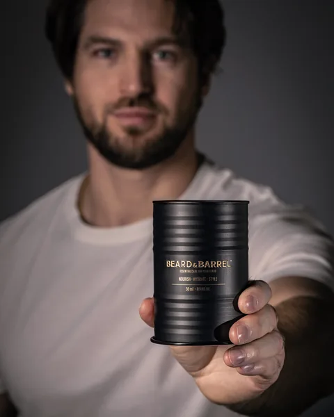 A man holding the Beard & Barrel tin
