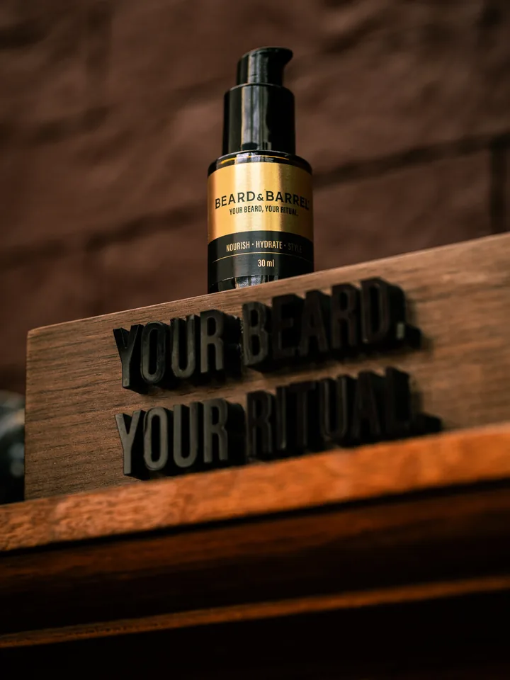 Beard & Barrel oil beside a carved wooden sign reading ‘Your beard. Your ritual.’