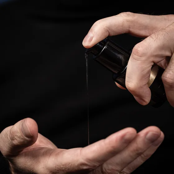 Dispensing drops of beard oil into an open palm